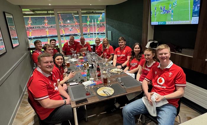 A group of guests smiling at the camera while enjoying matchday hospitality in a premium lounge at Principality Stadium.